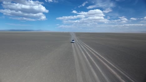Aerial-drone-shot-of-a-van-riding-in-desert-zoom-out